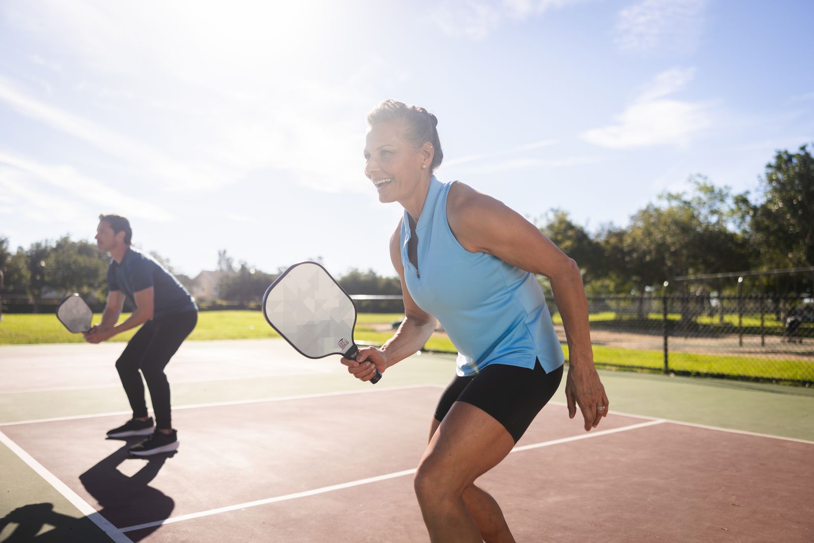 Two pickleball players in ready position during a rally on an outdoor court